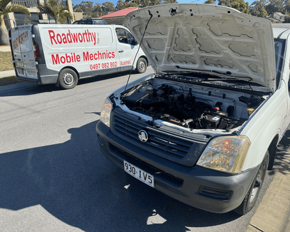  "Ausmec Mobile Mechanic conducting a Burpengary East Mobile Roadworthy (Safety Certificate) inspection on a ute on-site." Car with open hood on a road, with a Roadworthy Mobile Mechanics van in the background.