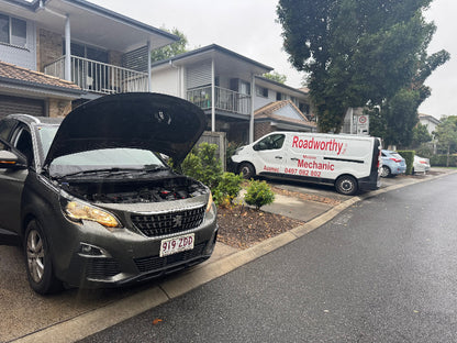 A complete pre purchase car inspection Near Albion, including a full scan and thorough check of the vehicle in the seller's driveway. Car with open hood on a residential street, Radworthy van parked nearby
